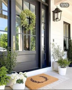 the front door is decorated with wreaths and potted plants