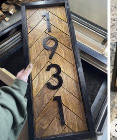 a person holding up a wooden sign with numbers and letters on it in front of an oven