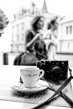 a coffee cup sitting on top of a table next to a camera