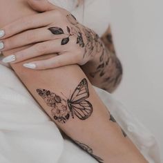 a woman's arm with tattoos and flowers on her left arm, holding onto the wrist