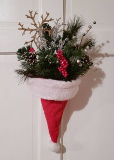 a red christmas stocking hanging on a door with pine cones and berries in it