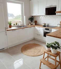 a kitchen with white cabinets and wooden counter tops, potted plants on the island