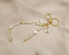 a white beaded bracelet with a gold charm