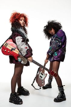 two young women with red hair are holding guitars and posing for the camera in front of a white background