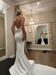 a woman standing in front of a mirror wearing a wedding dress