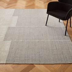 a chair sitting on top of a wooden floor next to a gray rug and black chair