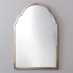 an arched mirror mounted on the wall above a sink in a room with gray walls