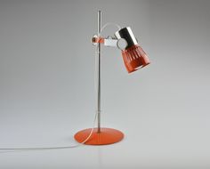 an orange table lamp with a black and white light on it's base, sitting on a gray surface