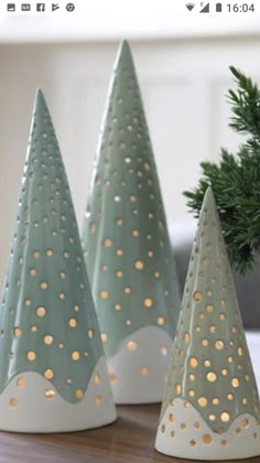 three ceramic christmas trees sitting on top of a wooden table