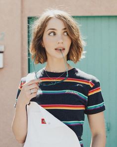 a young woman holding a white bag in her hand and looking up at the camera