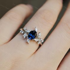 a woman's hand with a blue and white diamond ring on top of it