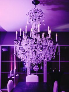 a chandelier hanging from the ceiling in a room with purple walls and chairs