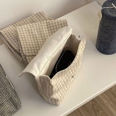 a bag sitting on top of a white table next to a blue can and a black cup