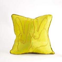 a yellow pillow with two rabbits on it