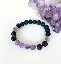 Amethyst and Lava Rock Bracelet, Essential Oil Diffuser Bracelet, Healing Gemstone Bracelet This high vibrational semi-precious gemstone bracelet is handmade with soothing lilac amethyst crystal and lava stone complimented with stainless steel spacers. 8mm Amethyst and black lava rock is strung on a strong stretch cord for a comfortable fit for your wrist. Boost your mood anytime around your wrist wearing Lava Rocks that are uniquely porous so they capture and carry oil releasing the scent like Healing Bracelet With Gemstone Beads And Lava Stone, Healing Lava Stone Bracelets With Gemstone Beads, Black Amethyst 8mm Bead Bracelets, Amethyst Stretch Bracelet With 8mm Beads As Gift, Black Amethyst Bracelets With 8mm Beads, Black Amethyst Bracelet With 8mm Beads, Amethyst Bead Bracelets For Healing, Amethyst Beaded Bracelet, Lava Stone Jewelry