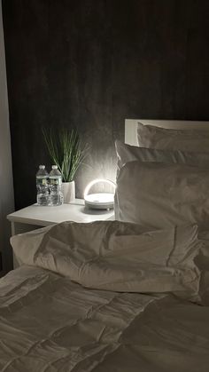 a bed with white sheets and pillows next to a night light on the side table