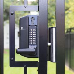 an electronic device mounted to the side of a metal gate in front of a green yard