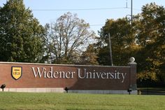 a sign for the widener university campus in front of some trees and grass