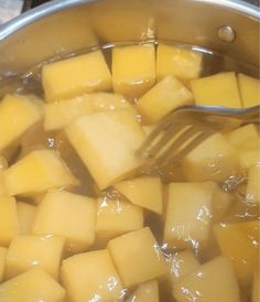 cubed cheese being cooked in a pot with a spoon