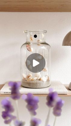 a glass jar filled with shells on top of a shelf next to a mushroom lamp