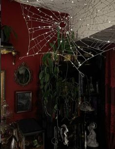 a spider web hanging from the ceiling in a living room with red walls and decorations