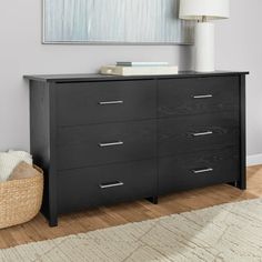 a black dresser in a living room next to a lamp and rug on the floor