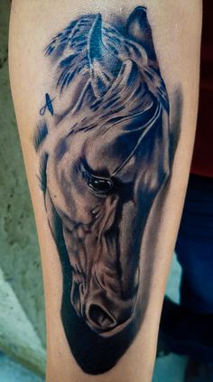 a black and grey horse tattoo on the leg