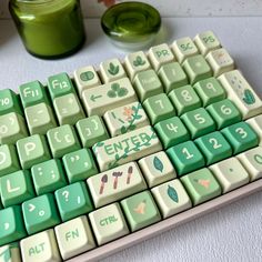 a green and white computer keyboard sitting on top of a table next to a cup