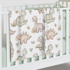 a baby crib bed with dinosaurs on it and white rails in front of the crib