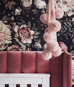 a floral wallpaper with pink flowers and pom poms hanging from the ceiling