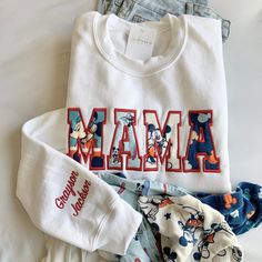 The Embroidered Mama Sweatshirt, adorned with a baby outfit appliqué, offers a heartwarming keepsake idea for mothers, making it an ideal gift for Mother's Day, embodying both sentimentality and style in one mom sweater gift. How to order: 1. Select sweatshirt SIZE and COLOR  2. Select NAME ADD ON 3. In the personalization box please include:  🧵 Text for chest (3-5 letters - MAMA, DAD, DADA, PAPA, GIGI, NANA, etc..) 🧵 Name of child(ren) if needed 🧵 Thread color  🧵 Font Number (thread color i Mothers Day Keepsake, Child Clothes, Font Number, Mom Sweater, Gift For Mothers Day, Personalized Gifts For Mom, Mama Sweatshirt, Sweater Gift, Baby Outfit