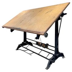 an old wooden table with metal legs and wheels on it's base, against a white background