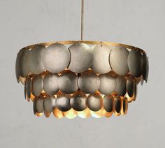 a chandelier made out of metal discs and hanging from a brass chain on an isolated white background