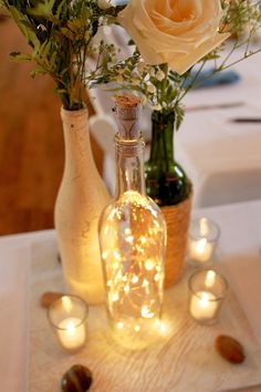 two vases filled with flowers and lit candles on a table