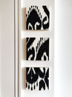 three black and white paintings hanging on the side of a refrigerator freezer in a kitchen