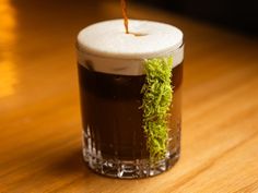 a drink with moss growing on the rim is sitting on a wooden table, ready to be eaten