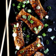 grilled salmon with sesame seeds, scallions and green onions on a black surface