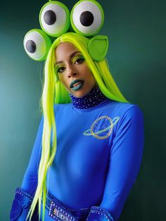 a woman with bright green hair and monster eyes on her head wearing a blue bodysuit