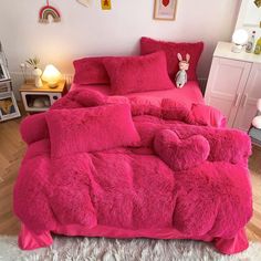 a bed with pink comforter and pillows in a room next to two lamps on the wall