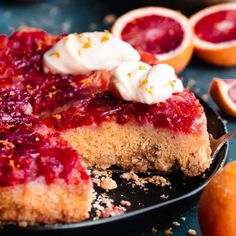 a close up of a cake on a plate with blood oranges in the background