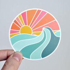 a hand holding up a sticker with the sun and water