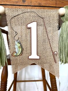 a fishing themed 1st birthday banner on a chair with some tassels hanging from it