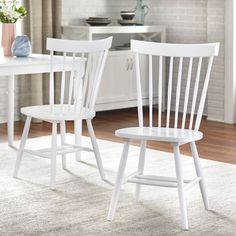 two white chairs sitting next to each other on a rug