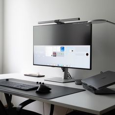 a computer monitor sitting on top of a white desk next to a keyboard and mouse