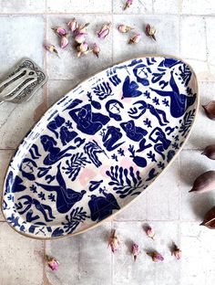 a blue and white plate sitting on top of a tile floor next to garlic cloves