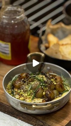 a pan filled with food sitting on top of a wooden table next to a jar of honey