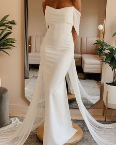 a woman in a white wedding dress is looking at herself in the mirror