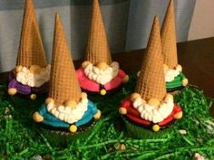 four cupcakes with cones on top of them