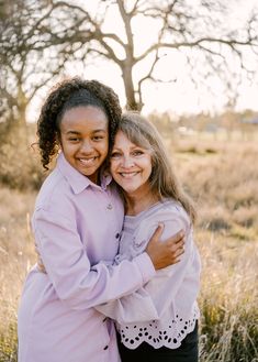 two girls hugging each other in a field