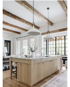 a large kitchen with an island in the middle and wooden beams on the ceiling above it